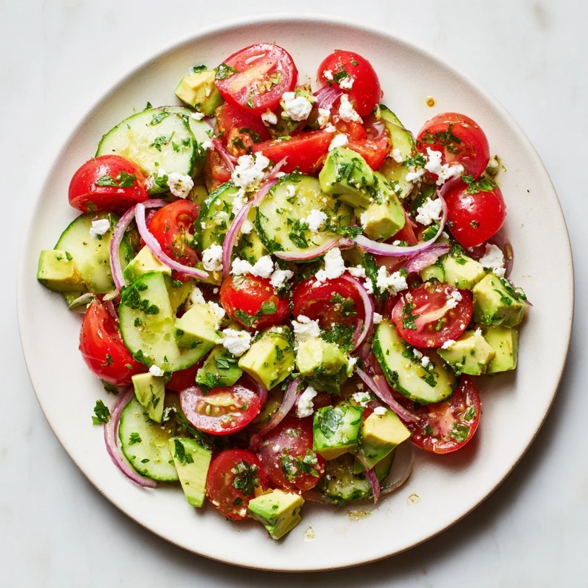 Close-up of a vibrant Cucumber, Tomato, and Avocado Salad with creamy avocado, and crumbled feta cheese.