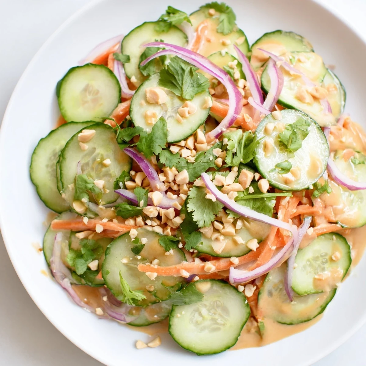 A vibrant Thai-Style Peanut Cucumber Salad, tossed in a creamy peanut dressing with visible peanuts.