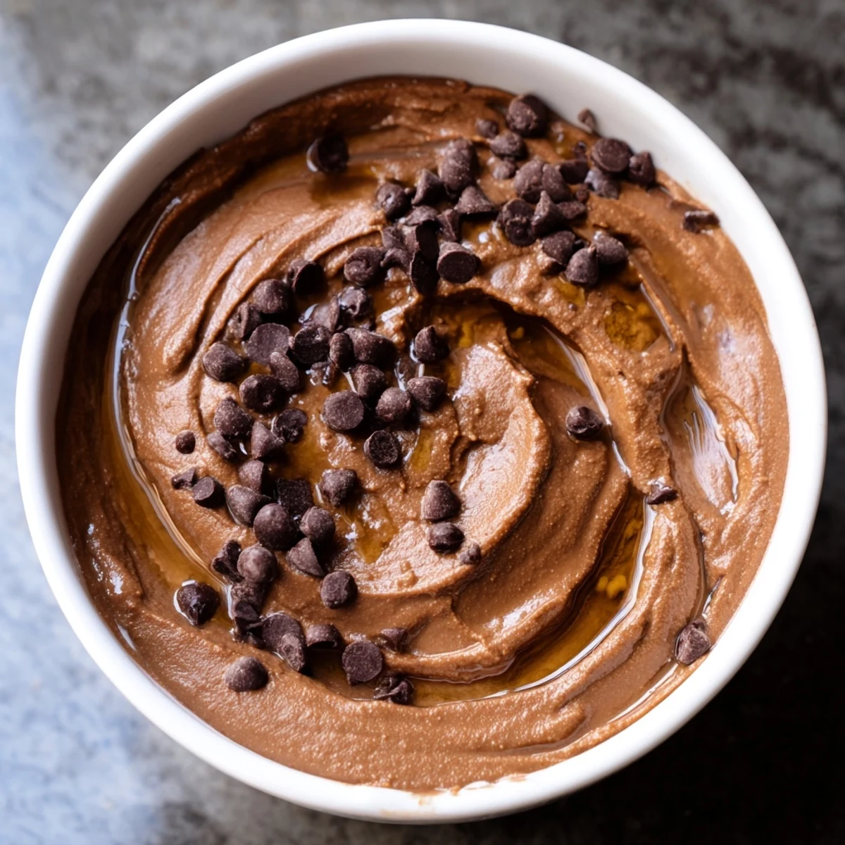 A rich, dark photo of smooth, creamy chocolate hummus ready to be scooped up.