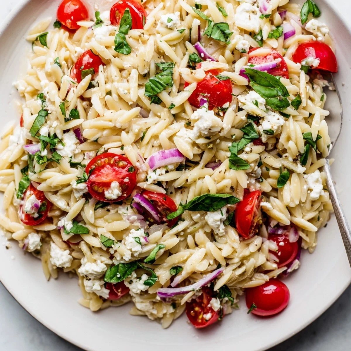 Vibrant Tomato Feta Orzo pasta salad, showing the feta's creamy texture in a Mediterranean bowl.