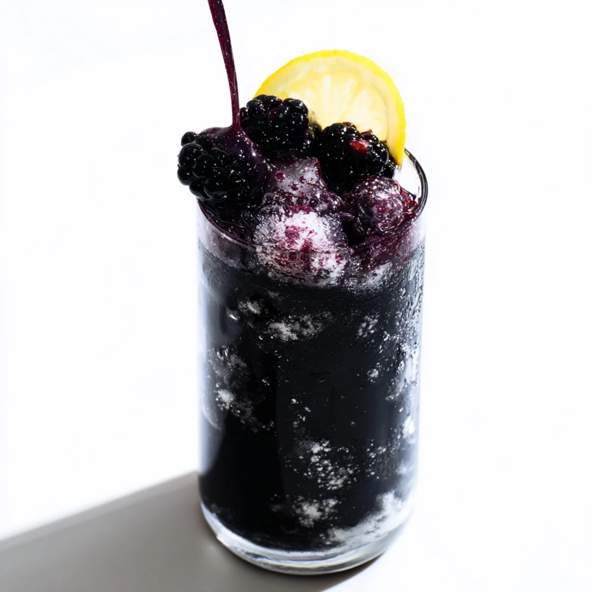This striking Dark Matter Mocktail features inky black layers contrasted with vibrant garnishes and crushed ice.