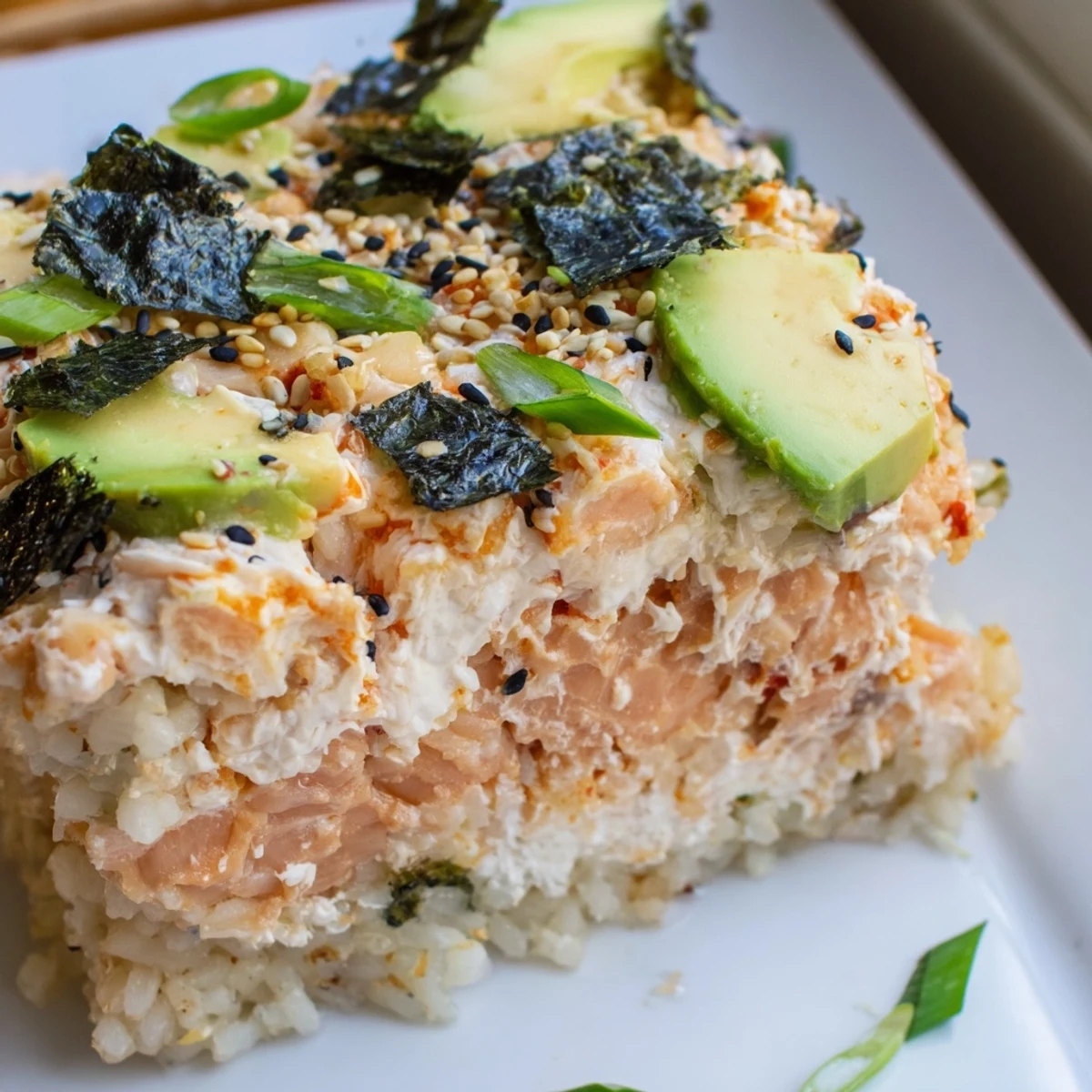 Warm, bubbling Sushi Bake Casserole, topped with avocado, sesame seeds and crispy nori, perfect for dinner.