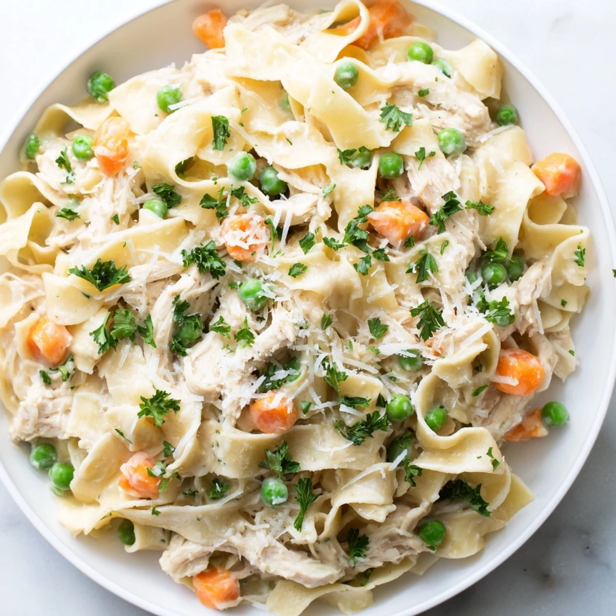 A steaming skillet of Spring Chicken Noodle Skillet showcases creamy sauce coating tender noodles, peas, and carrots for a cozy dinner.  