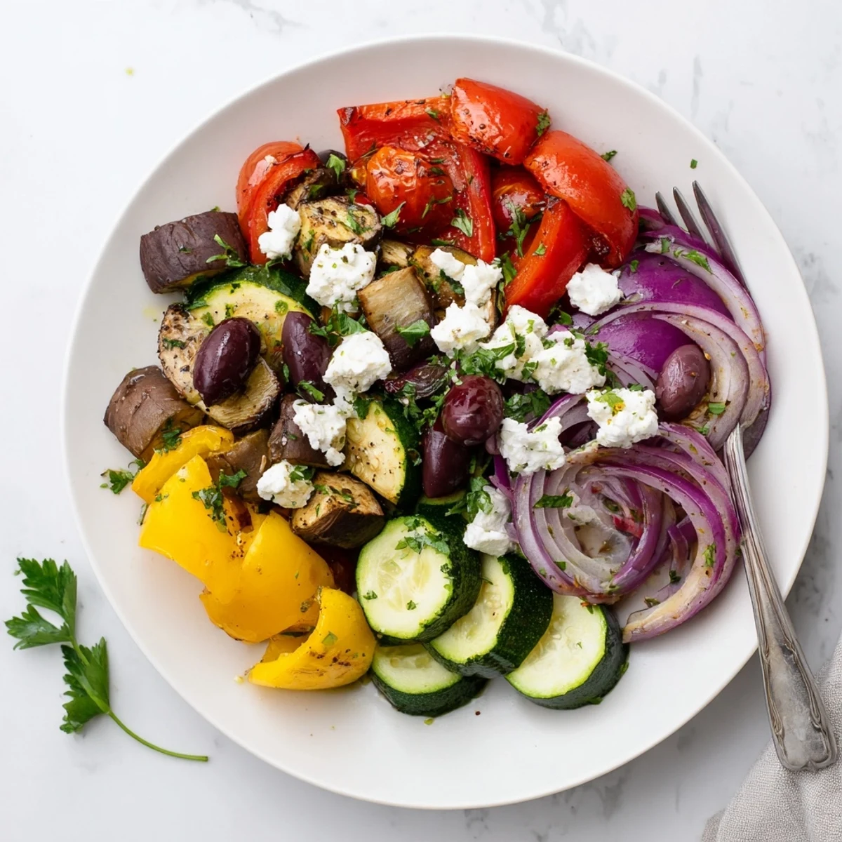 Warm roasted Mediterranean vegetables, including red bell peppers and eggplant, are tossed with olives and feta in this Roasted Greek Salad.