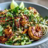 A close-up of a colorful Asian Noodle Bowl garnished with chopped peanuts and cilantro.