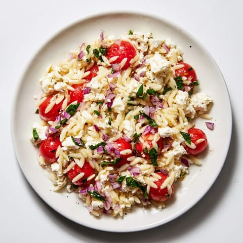 Close-up of freshly tossed Tomato Feta Orzo, showcasing ripe tomatoes and flavorful herbs.