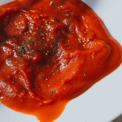 Smooth, red sauce coats a plate of twirled pasta, garnished with fresh basil and a sprinkle of Parmesan cheese.