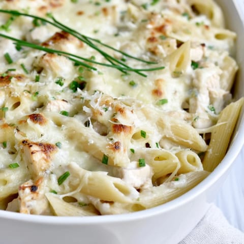 Steam rises from a serving of Chicken Ranch Pasta Bake, showing tender penne, diced chicken, and melted cheese.