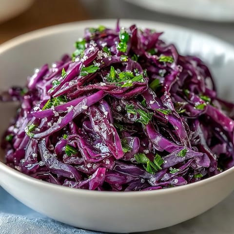 A bowl of Red Cabbage Coleslaw With Apple and Parmesan highlights fresh parsley garnish and shaved cheese.