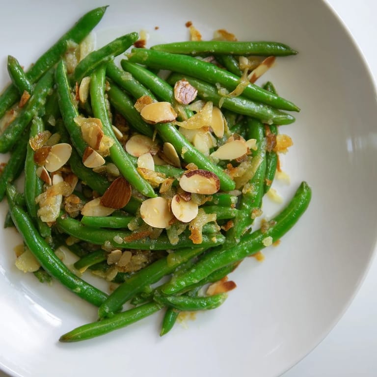 Golden, toasted almonds top the vibrant Sautéed Green Beans, showcasing the garlic's fragrance.