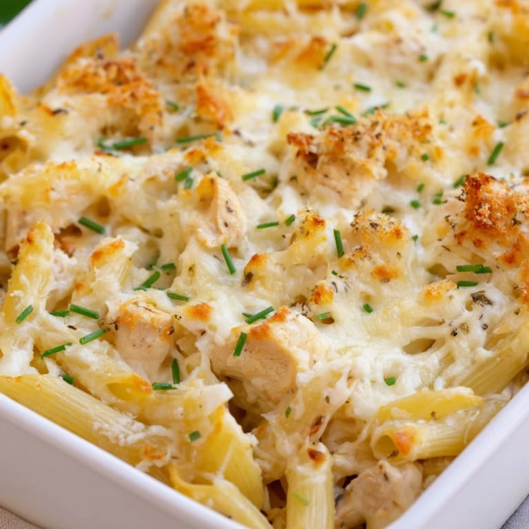 Close-up of a freshly baked Chicken Ranch Pasta Bake with a golden, bubbly cheese topping and herbs.