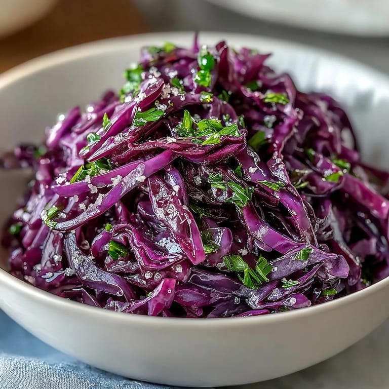 A bowl of Red Cabbage Coleslaw With Apple and Parmesan highlights fresh parsley garnish and shaved cheese.